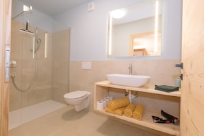 Un baño con ducha, inodoro, lavabo y espejo.