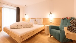 Un lit en bois avec une tête de lit, un fauteuil turquoise et une petite table de chevet.
