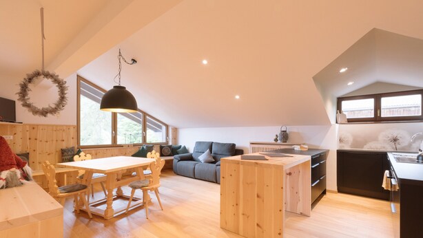 Un loft spacieux comprenant un coin repas, un canapé, une cuisine et de grandes fenêtres.