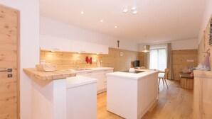 A modern kitchen with white cabinetry, wooden accents, and a central island. - Beautiful and Cozy Holiday Home “Ferienwohnung SHUPF Wieserhof” with Mountain View, Balcony, Shared Garden & WiFi; Parking Available (Aldein)