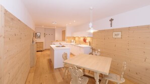 A modern kitchen with wooden walls, a central island, and a dining area with a table and chairs. - Beautiful and Cozy Holiday Home “Ferienwohnung SHUPF Wieserhof” with Mountain View, Balcony, Shared Garden & WiFi; Parking Available (Aldein)