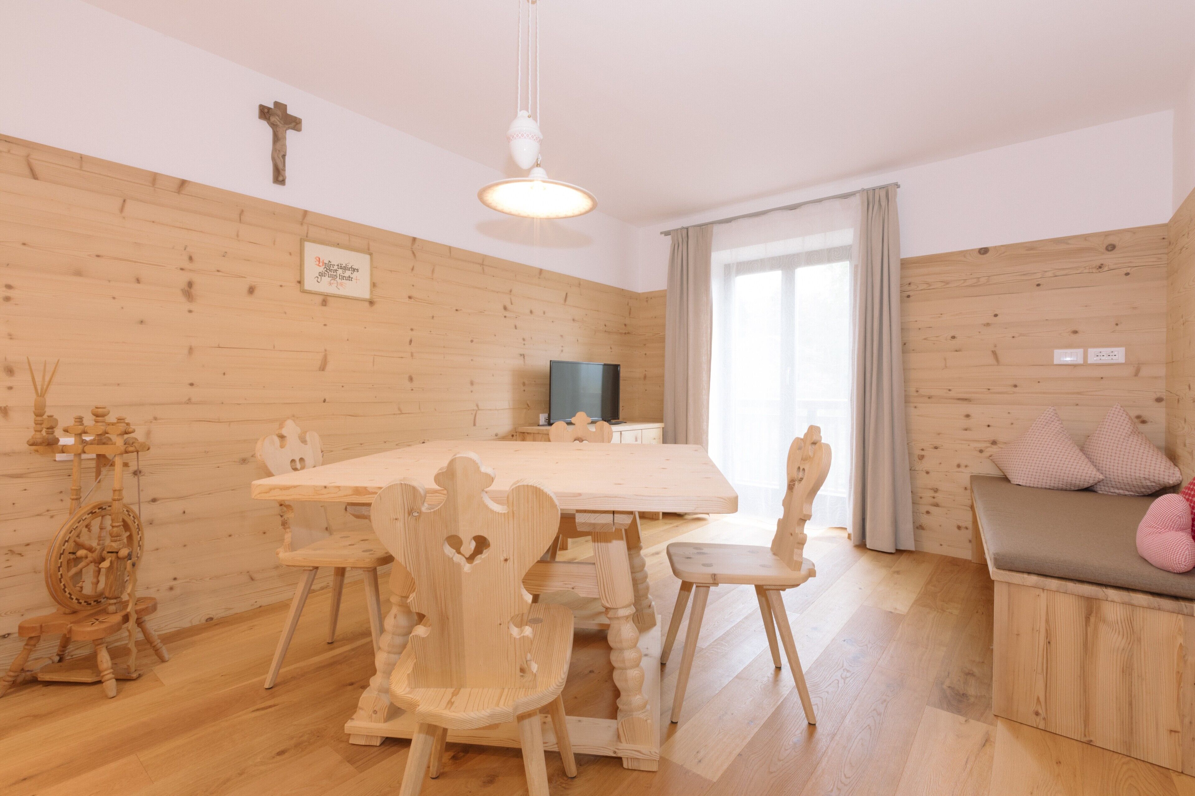 Een kamer met houten lambrisering, een eettafel, stoelen, een televisie en een bank.