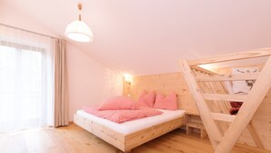 A room with a wooden bunk bed, a single bed with red checkered bedding, a wooden floor, a window with curtains, and a hanging light fixture. - Beautiful and Cozy Holiday Home “Ferienwohnung SHUPF Wieserhof” with Mountain View, Balcony, Shared Garden & WiFi; Parking Available (Aldein)