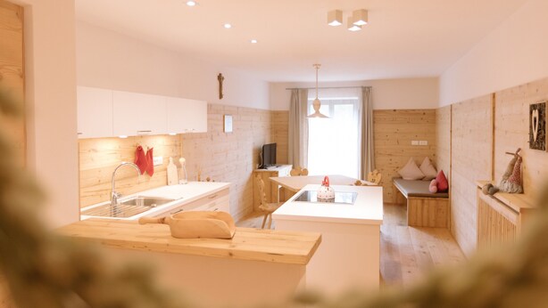 A modern kitchen with wooden cabinetry, a central island, and a dining area with a bench. - Beautiful and Cozy Holiday Home “Ferienwohnung SHUPF Wieserhof” with Mountain View, Balcony, Shared Garden & WiFi; Parking Available (Aldein)
