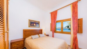 Une chambre à coucher avec un lit, une table de chevet, une fenêtre avec des rideaux et un tableau au mur.