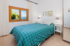 A bedroom with a bed, two bedside tables, a window with a view, and a mirror.