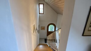 Una escalera estrecha con escalones de madera y un suelo con estampado.