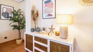 Een goed verlichte kamer met een witte console tafel, decoratieve objecten, een lamp en een abstract schilderij in een lijst aan de muur.