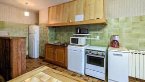 Una cocina compacta con armarios de madera, un refrigerador, un microondas, un tostador y una cafetera.