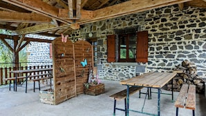 Un edificio rústico de piedra con vigas de madera, un banco, una mesa y una decoración con mariposas.
