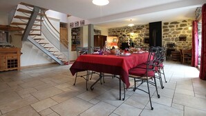 A dining area with a red tablecloth, chairs, and a staircase. - Restored 19th-Century Farmhouse with Garden, Near Trails & Attractions (Saint-Julien-Chapteuil)