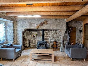 A cozy living room with a stone fireplace, wooden beams, and two grey sofas.