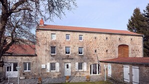 Un bâtiment en pierre doté de nombreuses fenêtres, d’une porte centrale et d’une petite cour.
