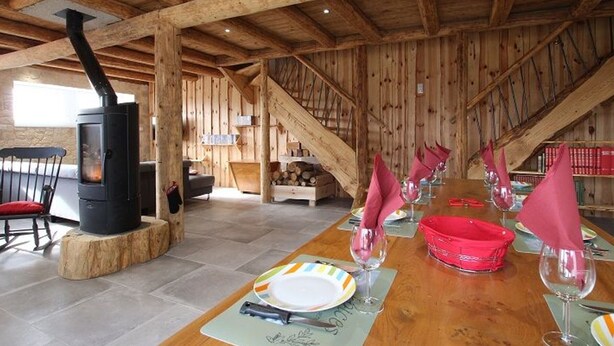 Ein Holzkaminzimmer mit einem langen Esstisch, gedeckt für eine Mahlzeit, einem Kamin und einer Treppe.