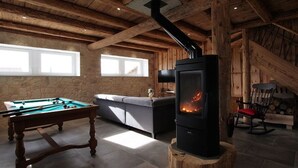Ein gemütliches Zimmer mit Billardtisch, einer Couch und einem Kaminofen.