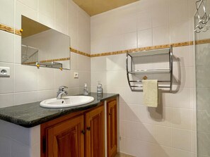 Ein Badezimmer mit Waschbecken, Spiegel, Handtuchhalter und Holzschränken.