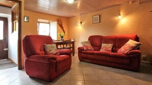 A living room with two red sofas, a wooden ceiling, and a tiled floor.