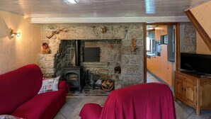 A living room with a stone fireplace, red sofas, and a television on a wooden cabinet.