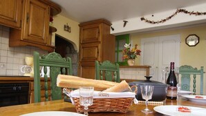 A dining table set with plates, a bottle of wine, a basket of bread, and a glass of water.