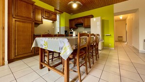 A kitchen with wooden cabinets, a dining table with chairs, and a refrigerator.