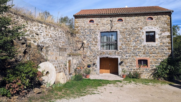A stone house with a tiled roof, a wooden door, and two windows.