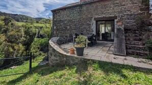 A stone building with a patio, outdoor seating, and a view of the countryside.