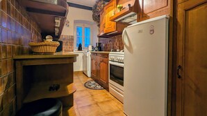 A kitchen with wooden cabinets, a white refrigerator, a stove, and a sink. - Charming House with Terrace, Garage, and Activities near Allier Gorges (Mazeyrat-d'Allier)