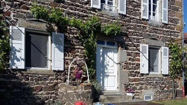 A stone building with white shutters, a wooden bench, and outdoor dining setup. - Charming House with Terrace, Garage, and Activities near Allier Gorges (Mazeyrat-d'Allier)