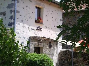 A rustic building with a stone facade, a small window with flowers, and a stone wall. - Charming Restored Pigeon House: Private Terrace, Swing Set, Near Loire River & Hiking Trails (Retournac)