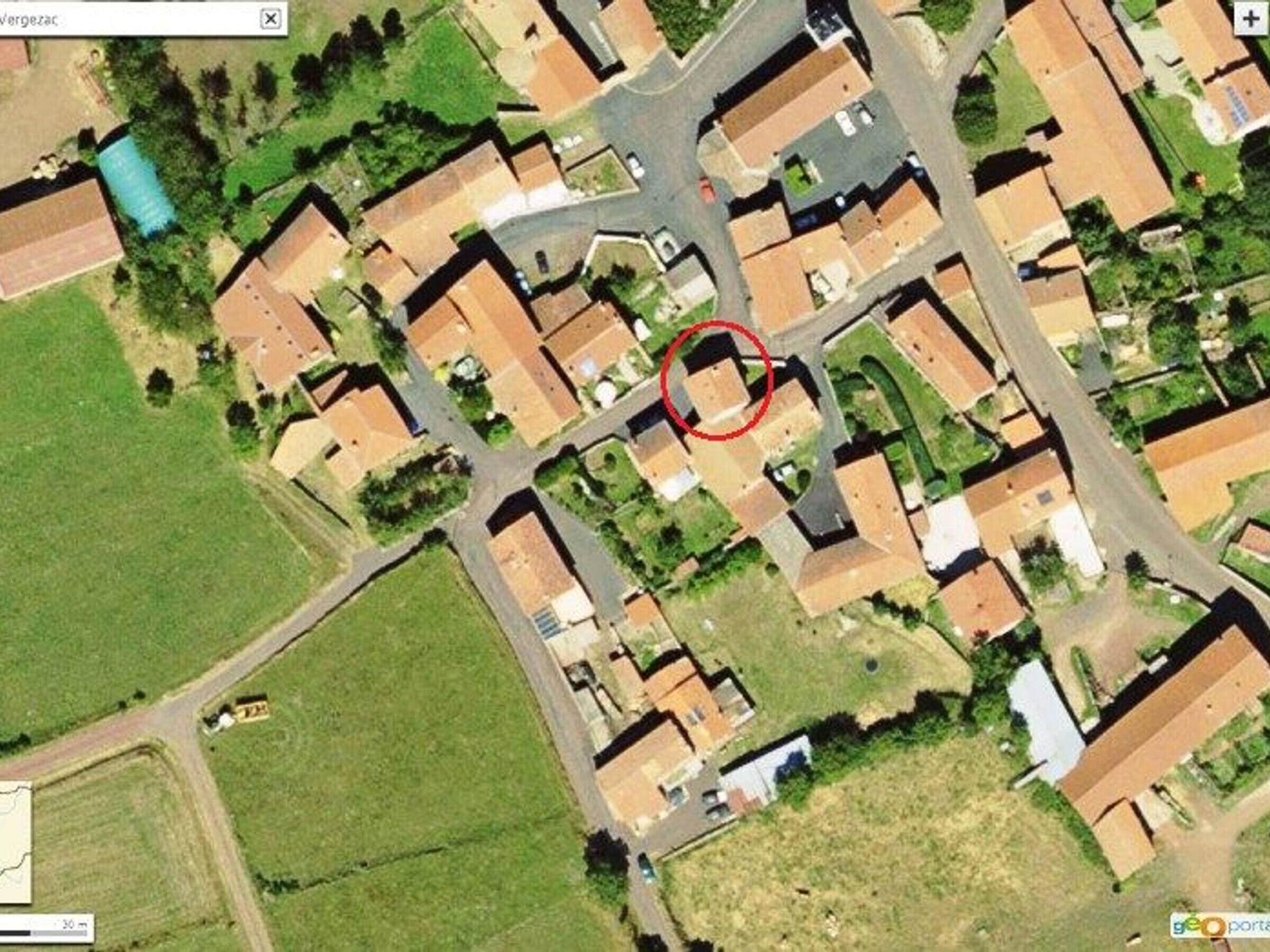 A satellite view of a residential area with houses, roads, and a small green space.