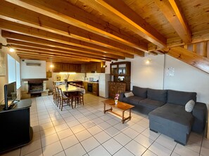 Un vaste espace de vie comprenant une table à manger, un canapé et une cuisine en arrière-plan.