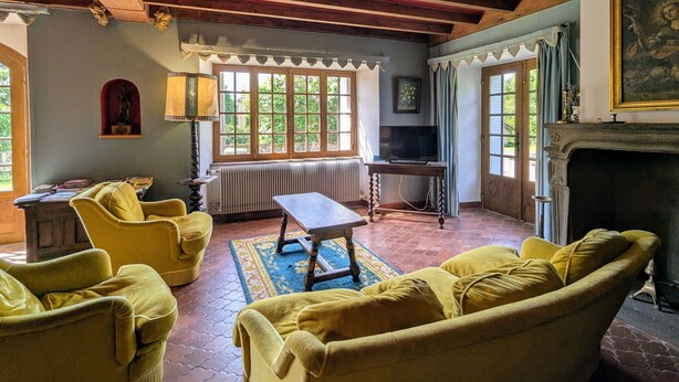 Un salon chaleureux avec des canapés jaunes, une table en bois et une cheminée.