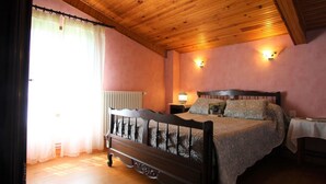 A bedroom with a wooden ceiling, a bed with a headboard, two bedside tables, and a window with curtains.