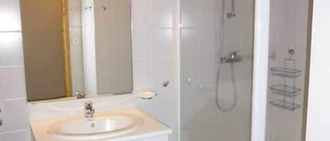A bathroom with a sink, mirror, and shower.
