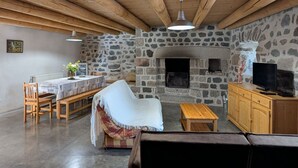 A rustic interior with a stone fireplace, wooden furniture, and a television. - Charming Village Farmhouse Sleeps 8 – Near Allier Gorges & Pradelles (Rauret)