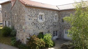 A stone building with a tiled roof, a small garden, and a wooden bench. - Charming Village Farmhouse Sleeps 8 – Near Allier Gorges & Pradelles (Rauret)