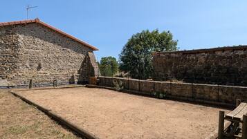 Une cour bordée de murs en pierre, avec une clôture en bois et un ciel dégagé.