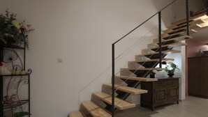 A modern staircase with wooden steps and metal railings, leading to a landing with a wooden cabinet and a potted plant. - Cozy 5-bedroom lodge near Freycenet-la-Cuche, perfect for families and friends, pet-friendly (Freycenet-la-Cuche)