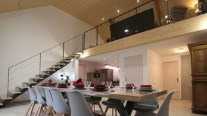 A modern dining area with a long table, grey chairs, and a staircase leading to an upper level. - Cozy 5-bedroom lodge near Freycenet-la-Cuche, perfect for families and friends, pet-friendly (Freycenet-la-Cuche)
