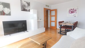Una sala de estar moderna con un televisor de pantalla plana, una mesa de centro de madera y un comedor con mesa y sillas.