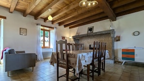 Un'area pranzo con un tavolo e sedie in legno, un camino in pietra e un orologio a parete.