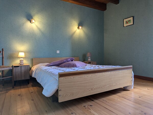 A bedroom with a wooden bed, two bedside lamps, and a framed picture on the wall.