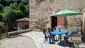 Edificio de piedra con un patio que tiene una mesa, sillas y una parrilla.