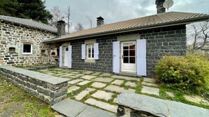 A stone house with a tiled roof, a small porch, and a stone pathway leading to the entrance.