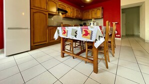 Une cuisine avec des meubles de rangement en bois, un réfrigérateur blanc et une table à manger accompagnée de chaises.