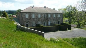 Un bâtiment en pierre doté d’une façade symétrique, de nombreuses fenêtres et d’une allée pavée.