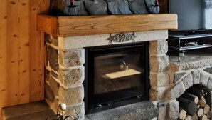 A stone fireplace with a wooden mantel, a TV mounted above it, and a year marker "1994" on the mantel.