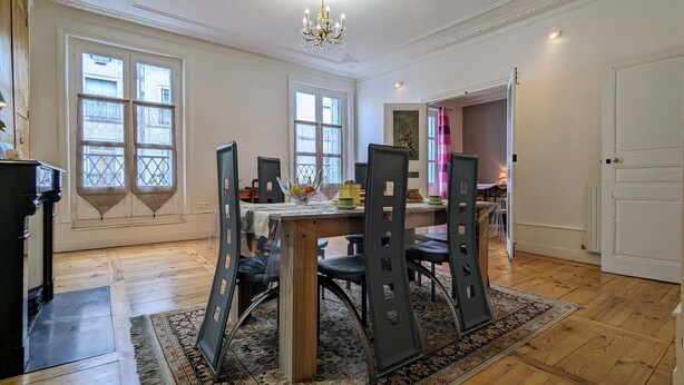 A dining area with a wooden table, chairs, and a chandelier. - Stunning 2BR Apartment in Historic Le Puy-en-Velay with Modern Amenities (Le Puy-en-Velay)