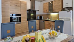 A modern kitchen with wooden cabinets, a built-in oven, a dishwasher, and a refrigerator. - Stunning 2BR Apartment in Historic Le Puy-en-Velay with Modern Amenities (Le Puy-en-Velay)
