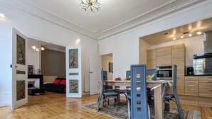 A spacious living area with a wooden floor, a dining table with chairs, and a kitchen area with wooden cabinets and modern appliances. - Stunning 2BR Apartment in Historic Le Puy-en-Velay with Modern Amenities (Le Puy-en-Velay)